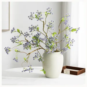 Vista dettagliata di rami di fiori artificiali viola in un vaso di ceramica testurizzato.