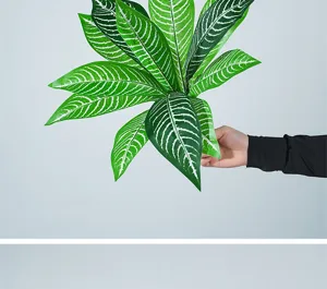 Detailed view of artificial green plant leaves with white stripes for floral arrangement.