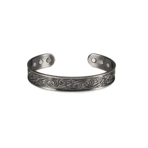 Detailed close-up of men vintage magnetic copper cuff bracelet with carved tribal pattern.