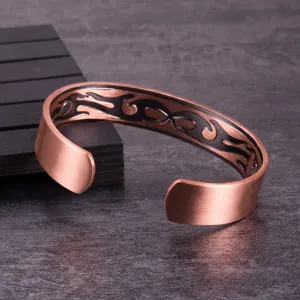 Close-up detail of the adjustable copper magnetic cuff bracelet with black tribal patterns.