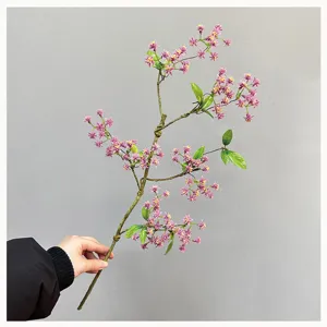 Dettaglio in primo piano di un ramo di fiori artificiali con piccoli fiori viola.