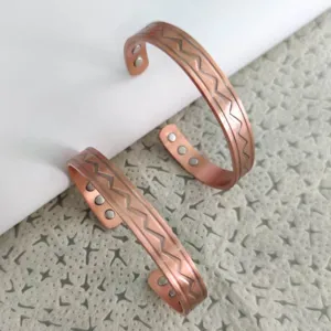 Primo piano dettagliato del braccialetto magnetico in rame regolabile con motivo a onde.