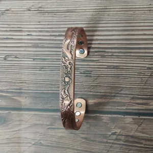 Vista dettagliata del bracciale magnetico in rame con incisione di drago e fenice.