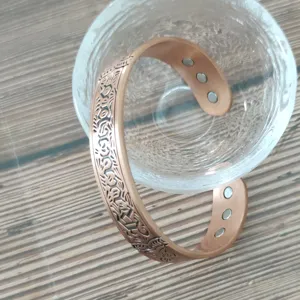 Magnetic copper bracelet detail view featuring vintage carved pattern and open design.