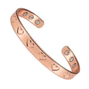 Primo piano dettagliato del bracciale magnetico in rame regolabile con motivo a cuori incisi.