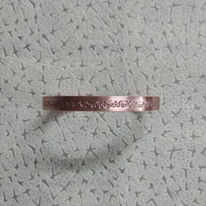 Vista di dettaglio del bracciale rigido in rame vintage con motivi floreali goffrati fini.