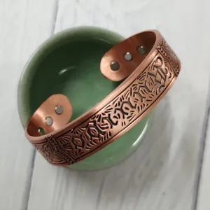 Close-up detail of the vintage copper magnetic bangle bracelet, showing engraved patterns.