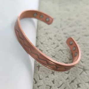 Dettaglio bracciale rigido magnetico in rame con motivo a zigzag e magneti interni.