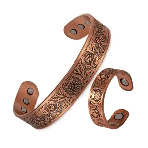 Close up view of copper magnetic bracelet and ring featuring embossed floral patterns details.