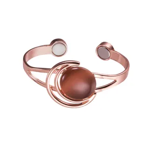 Detailed view of copper magnetic cuff bracelet with moon sun design and brown gemstone.