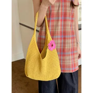 Dettaglio borsa a spalla in maglia traforata gialla, design a rete casual con fiore rosa.