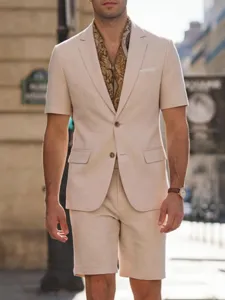 Outdoor street detail view of men's beige short sleeve blazer suit set with paisley scarf.