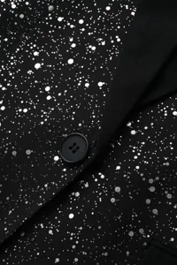 Détail élégant de blazer scintillant noir pour homme avec motif argenté et un seul bouton.