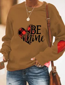 Close-up detail of the brown sweatshirt featuring heart graphic and lovely print.