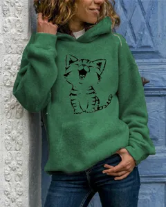 Detail view of the green hooded sweatshirt featuring a cute cartoon cat graphic and pocket.