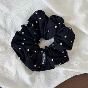 Close-up detail of a Korean style black polka dot hair scrunchie, showing soft fabric texture.