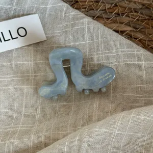 Gros plan sur la pince à cheveux en acétate bleue, forme chenille mignonne, accessoire.