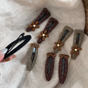 Detailed view of vintage brown floral fabric snap hair clips with cute flower and bow charms.