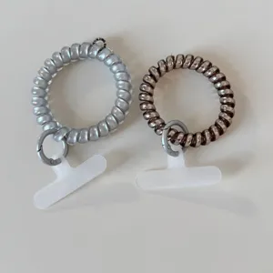 Detail view of telephone cord hair ties with mobile phone tether tabs and metal rings, multi-purpose.