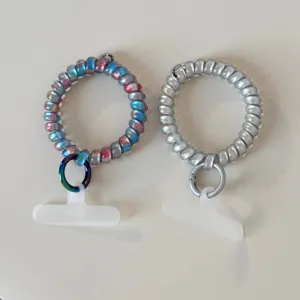 Gradient rainbow and silver telephone wire hair ties with metal rings and tether tabs for phone.