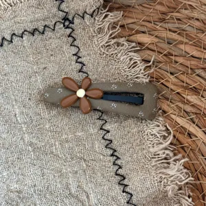 Brown fabric hair clip detail shot showing floral pattern and cute flower decoration clearly.