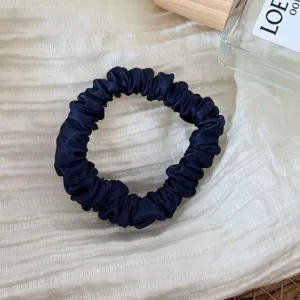 Navy blue silk scrunchie detail shot, elegant satin hair tie texture for daily chic hairstyles.