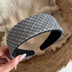 Gros plan détaillé sur le serre-tête en tissu large, rayé noir et gris, design minimaliste.