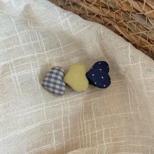 Primer plano detallado de lindas pinzas para el cabello con forma de corazón y lunares a cuadros.