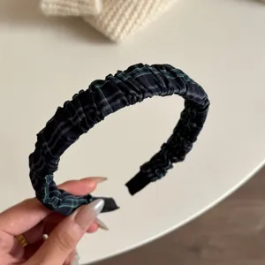 Primo piano dettagliato di un elegante cerchietto stretto a quadri con ruche nero e verde.