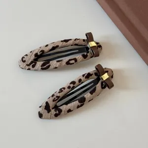 Vista detallada de pinzas para el cabello con estampado de leopardo y lazos marrones de moda.
