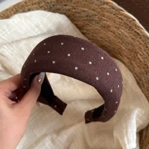 Gros plan détaillé d'un serre-tête en tricot marron à pois, accessoire en tissu doux.