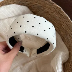 Gros plan détaillé d'un serre-tête en tissu blanc de style coréen à pois noirs mignons.