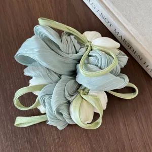 Gedetailleerd overzicht van de elegante tulpenhaarscrunchie met parelgaren bloemdesign groen.