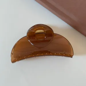 Dettaglio molletta per capelli traslucida marrone, elegante accessorio a mezzaluna.