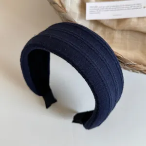 Detail de serre-tete en tissu côtelé bleu foncé montrant une surface texturée et large.