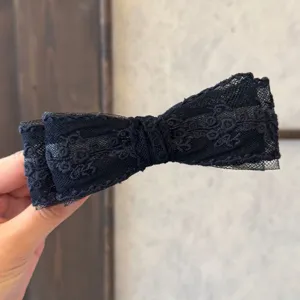 Vue de détail d'une pince à cheveux noire avec un nœud en dentelle et tulle élégant.