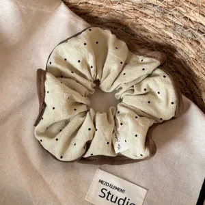 Gedetailleerd overzicht van grote stippen haarscrunchie met bruine rand, zachte stof.