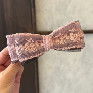 Vue détaillée d'une pince à cheveux nœud en dentelle rose avec des couches de résille.