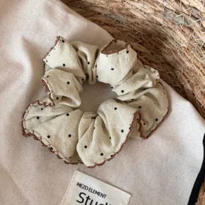 Beige haarelastiekje met zwarte stippen en bruine rand, stijlvol haaraccessoire voor dames.
