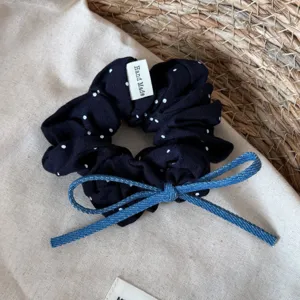 Close-up van het donkerblauwe gestippelde haarelastiek detail met een denim strik.