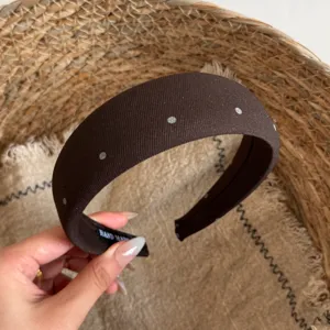 Close-up van de bruine stoffen haarband met stippen, stijlvol haaraccessoire voor dames.