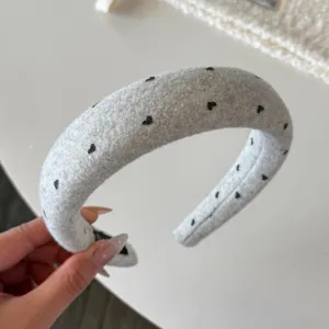 Vue détaillée du serre-tête en laine grise avec joli motif de cœur noir, texture douce.