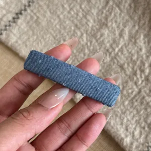 Gros-plan sur la barrette à cheveux en tissu denim bleu, détail de l'accessoire coiffure.
