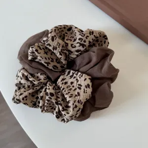 Primer plano de un coletero elegante de tela marrón y estampado de leopardo, textura suave.