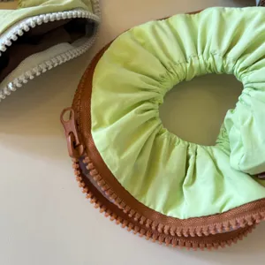 Close-up detail of creative zipper style hair scrunchie, green fabric with brown teeth.