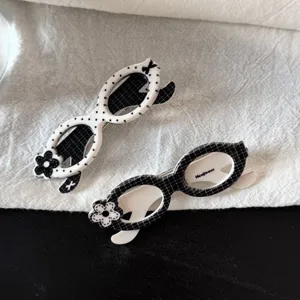 Gros plan détaillé de jolies pinces à cheveux en forme de lunettes à carreaux et pois avec fleurs.