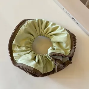 Detailed close-up of a trendy light green scrunchie with unique brown zipper edge design.