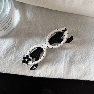 Jolie pince à cheveux en forme de lunettes à pois noirs et blancs avec joli décor floral élégant.