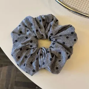 Dettaglio scrunchie grigio scuro a pois, elegante accessorio capelli in tessuto per uso quotidiano.