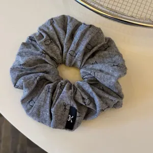 Elastico per capelli in tessuto grigio scuro con stampa di fiocco per acconciature quotidiane.